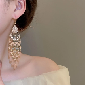 Close-up of vintage bohemian beaded fringe earrings worn by a model in soft lighting
