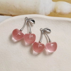 Detail of translucent pink cherry charms with silver metal stems and leaves for DIY jewelry