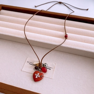 Détail d'un pendentif cœur vintage sur cordon ciré avec perles de bois et agate rouge