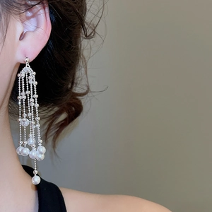 Detail of silver long tassel earrings with white pearls on a model's ear