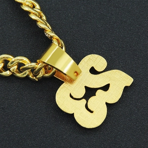 Close-up of gold brushed finish metal pendant with twist chain on black leather background