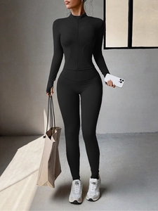 Détail d'un ensemble de yoga noir cintré avec haut zippé à manches longues et pantalon haut