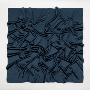 Detailed view of the smooth matte texture and soft ripples of a navy blue silk satin scarf