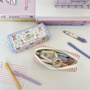 Close-up of cute plaid pencil case with pink bow print and embroidered happy patch