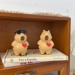 Détail de figurines capybara en bois avec cœurs rouges sur une étagère à livres