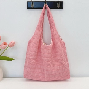 Detail showing the pink fabric tote bag with unique ribbed texture and wide shoulder strap
