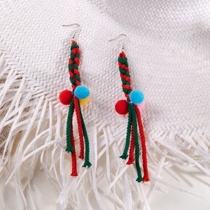 Detail of handmade Christmas earrings with colorful knit rope and soft fuzzy pom-poms