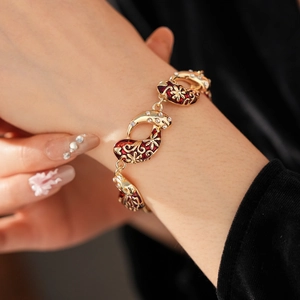 Detail of vintage gold bracelet with red floral enamel and zircons on a model wrist