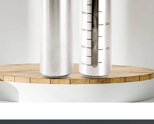Close-up of stainless steel oil sprayer with measurement scale on wooden base