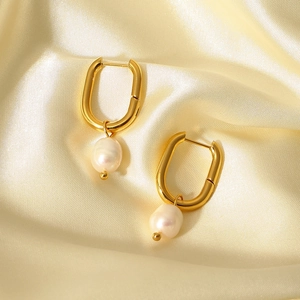 Detail of gold U-shaped hoop earrings with natural white pearl pendants on silk fabric