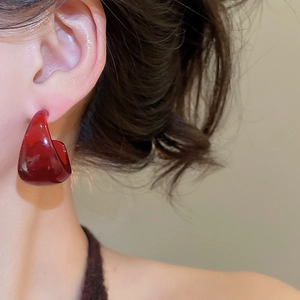 Close-up of translucent burgundy resin C-shape earring worn on model for vintage style