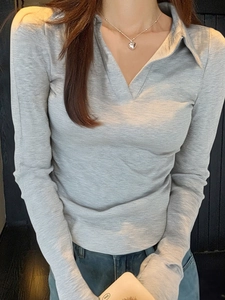 Détail du polo gris à manches longues et col en V avec un éclairage doux sur modèle