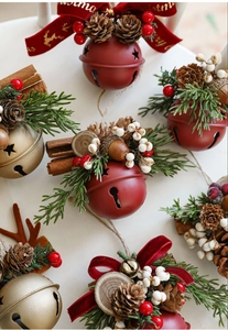 Detail of Christmas bell ornaments with pine cones, red berries and velvet bows