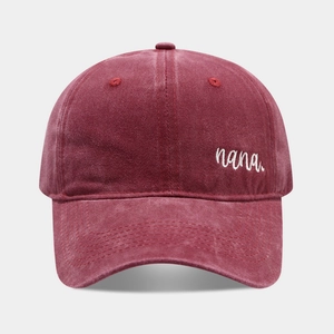 Close-up of burgundy washed denim baseball cap featuring white nana embroidery detail