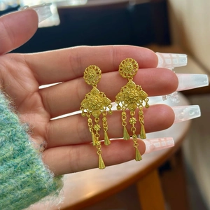 Dettaglio di orecchini a fiore dorati con eleganti pendenti a nappa metallica