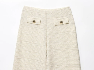 Gros plan d'un pantalon en tweed beige avec tissu texturé et boutons dorés