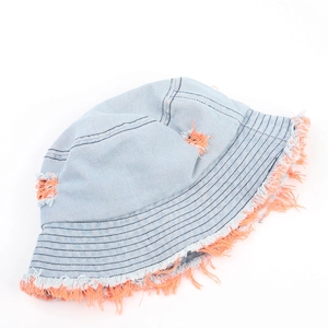 Dettaglio cappello a secchiello in denim blu con bordi sfrangiati arancioni e fori