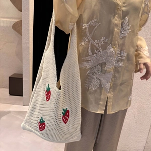 Detail of crochet knit tote bag featuring red strawberry patterns and openwork texture