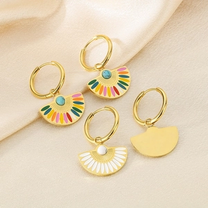 Macro shot of fan-shaped enamel earrings with turquoise stones on gold silk fabric