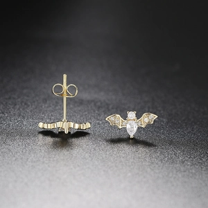 Gold-plated bat stud earrings with sparkling cubic zirconia on a black background