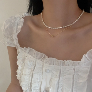 Close-up of double-layered freshwater pearl necklace with gold chain and spherical pendant