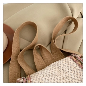Detail of straw woven bucket bag featuring canvas handles and colorful fabric trim