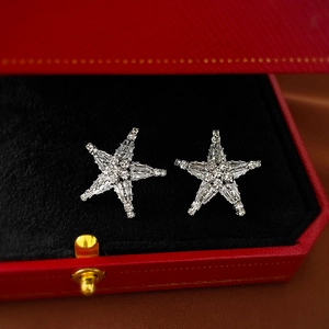 Macro shot of silver starfish stud earrings with sparkling crystals on black velvet