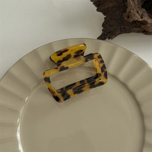 Detail view of large tortoise shell hair claw clip on a decorative beige tray