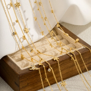 Elegant gold-plated titanium steel necklaces with diverse charms on a luxury jewelry box