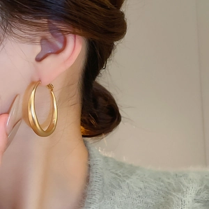 Close-up of elegant gold C-shaped hoop earrings with matte finish on female model