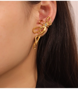 Close-up of golden ribbon bow ear cuff with a sparkling crystal on female ear