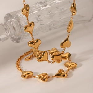 Detailed shot of 18K gold plated hollow heart necklace on a crystal glass stand