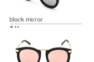 Close-up detail of black cat-eye sunglasses with pink mirror lenses and gold metal frame