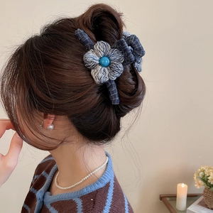 Detail of wool fabric flower hair claw clip with blue bead on elegant updo hairstyle