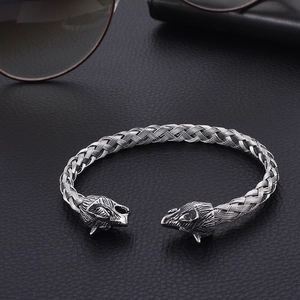 Detailed view of silver wolf head stainless steel braided bracelet on leather background