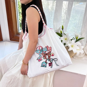 White nylon tote bag featuring colorful embroidery and red polka dot drawstring ropes