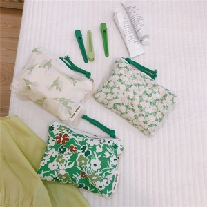 Detailed view of floral cotton pouches with zippers and wrist straps on a white background