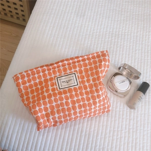 Detail of orange checkered cotton makeup bag with Time to Party label on white bedding