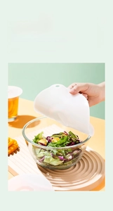 Food-grade silicone microwave lid cover showing flexible sealing on a glass salad bowl