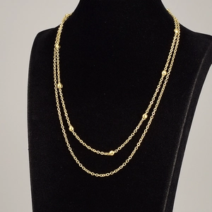 Double-layer gold beaded titanium steel necklace shown on a black velvet display stand
