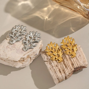 Dettaglio di orecchini a perno a forma di corallo oro e argento su blocchi materici