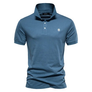 Gros plan du polo bleu en coton avec broderie blanche et étiquette de marque au col