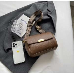 Détail du sac bandoulière en cuir marron avec large sangle jacquard géométrique
