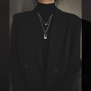 Close-up of double-layer silver titanium necklace with geometric pendant on black outfit