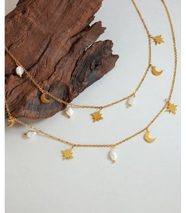 Detailed shot of star and moon charms with freshwater pearls on a gold necklace
