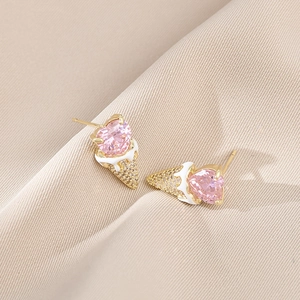 Detail of pink heart zircon earrings with gold ice cream cone design on fabric