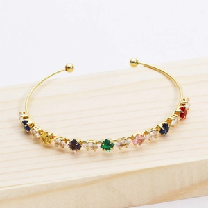 Detailed view of gold plated bracelet featuring colorful square cut zircon stones on wood
