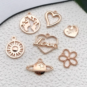 Macro shot of 7 rose gold alloy pendants including earth, heart, sun, and clover designs