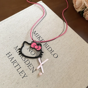 Detail of Hello Kitty pendant with pink bow on double cord necklace over a book