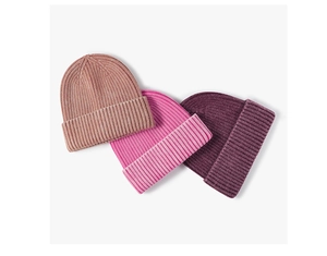 Detail der gerippten Strickstruktur von drei dicken Wintermützen in Pink und Lila